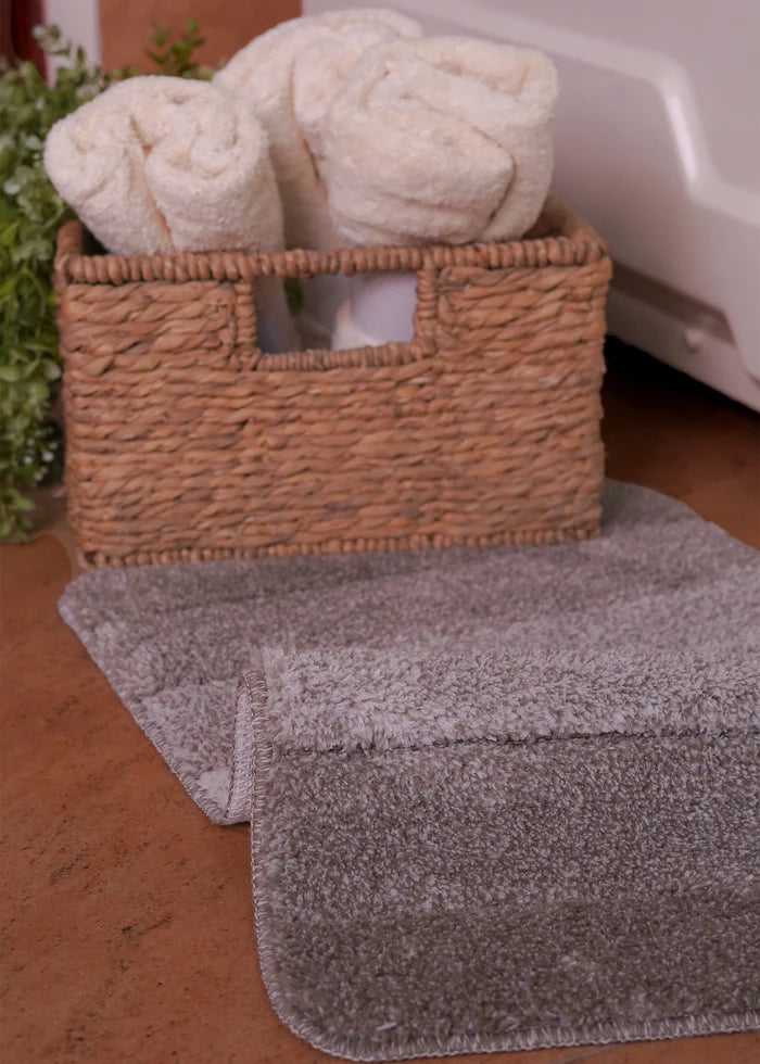Black rectangular bath mat with textured stripe pattern next to towels
