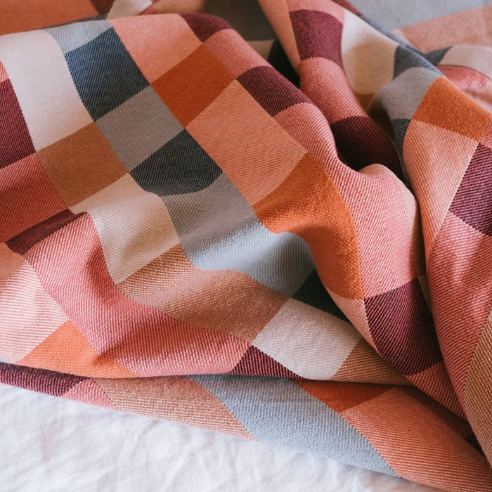 A folded blanket with a geometric pattern featuring shades of blue, brown, and beige.