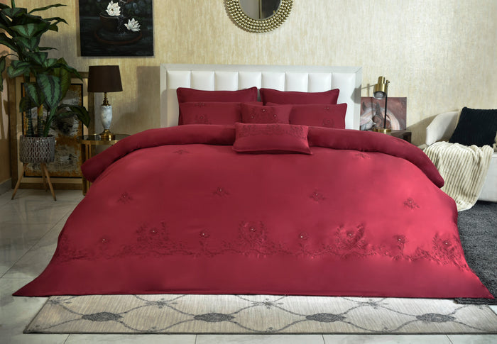 Red embroidered comforter laid on bed with coordinating pillows