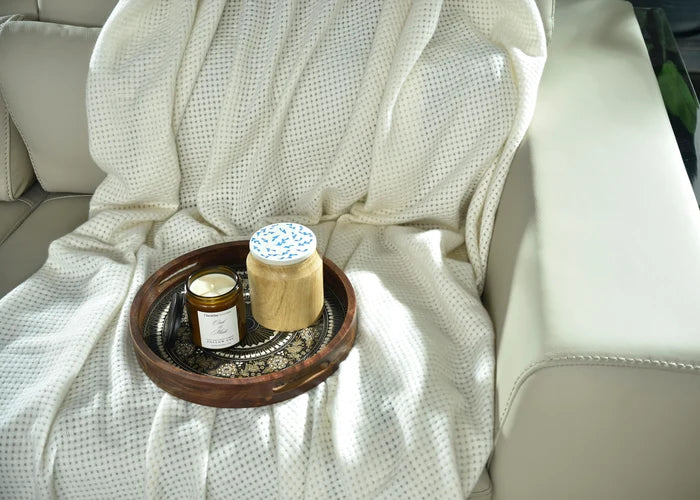 Light beige knitted throw blanket with waffle-knit texture and draped fold