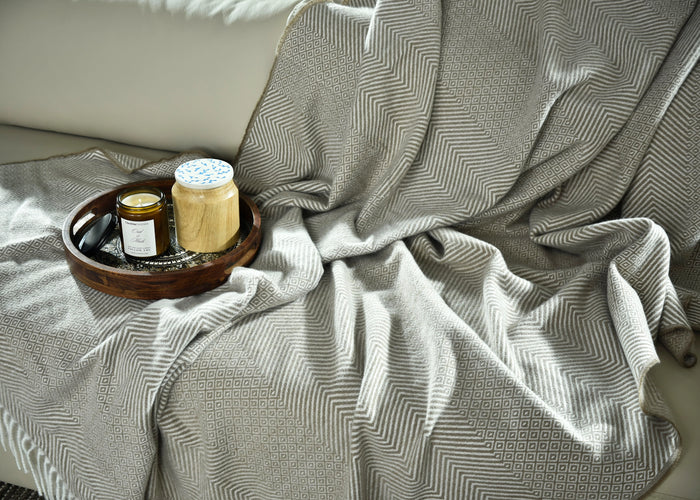 Light brown knitted throw with zigzag pattern and fringed border