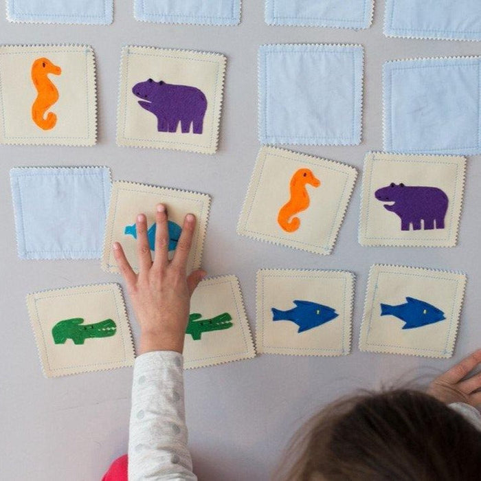 Child playing with educational cards featuring animals on a light gray background