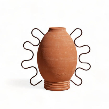 A terracotta amanda vessel with a sculptural design, featuring distinctive curved lines and hooks on the exterior.