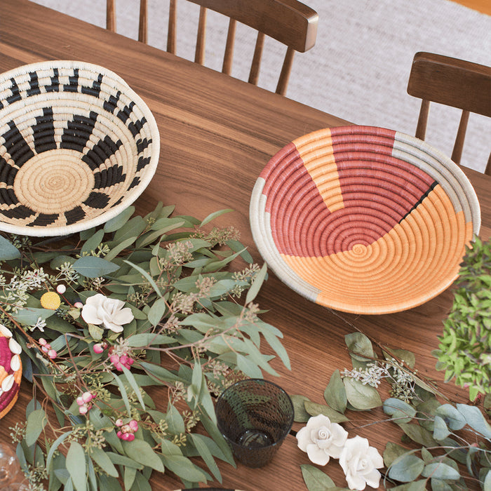 Decorative table setting with woven baskets and floral arrangements on a wooden table.