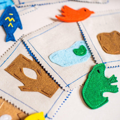 Colorful felt animal shapes on a grid-patterned fabric background