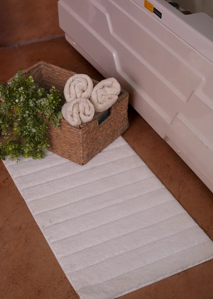 White polyester bath mat with ribbed texture, placed beside vanity storage