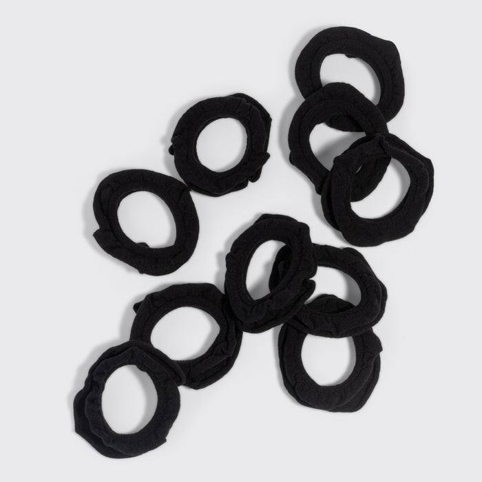Black petal hair elastics scattered on a grey background