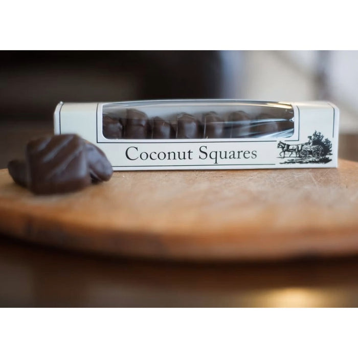 Box of coconut squares on a wooden surface