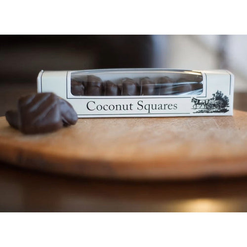Box of coconut squares on a wooden surface