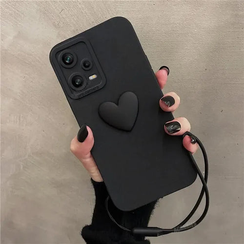 a woman holding a black phone case with a heart on it