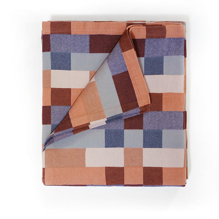 A folded blanket with a geometric pattern featuring shades of blue, brown, and beige.