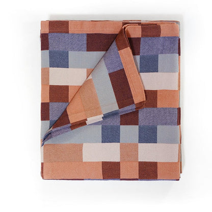 A folded blanket with a geometric pattern featuring shades of blue, brown, and beige.