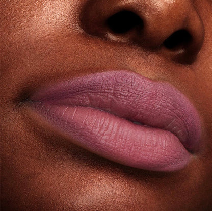 Close-up lips wearing ColourPop Flurries Ultra Matte Lip, a cool mauve shade with full-coverage, non-shiny finish, shown on deep skin under studio lighting to highlight smooth texture and crisp lip lines.