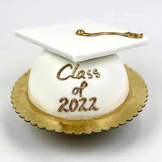White Grad Cap Cake featuring a golden tassel, gold base, and a “Class of 2022” message in gold