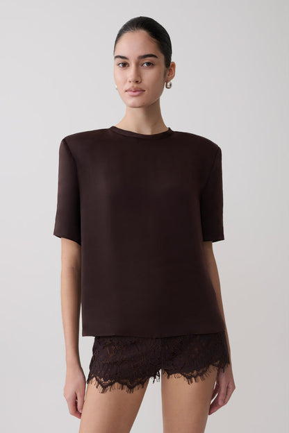 Woman wearing a dark brown shoulder pad short sleeve satin top with matching lace shorts.