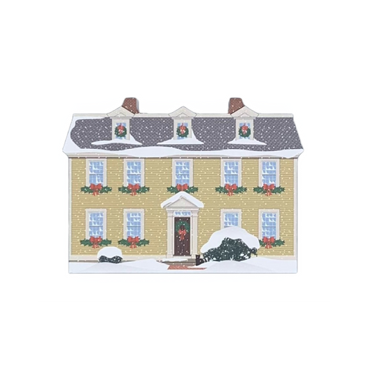 A miniature replica of the Crowninshield-Bentley House decorated for the holidays, made of wood with colorful details, on a white background.