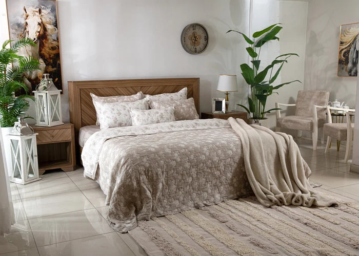 Beige 7-piece coverlet set on bed with patterned quilt and matching pillow shams