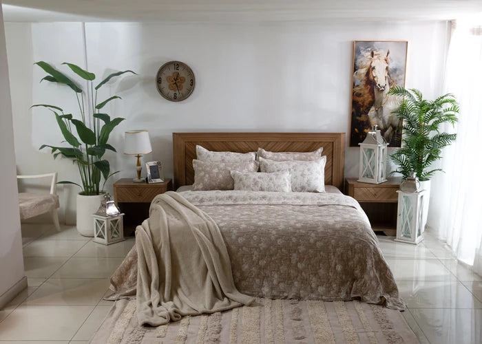 Beige coverlet set with textured quilt, two pillow shams, and draped throw on bed