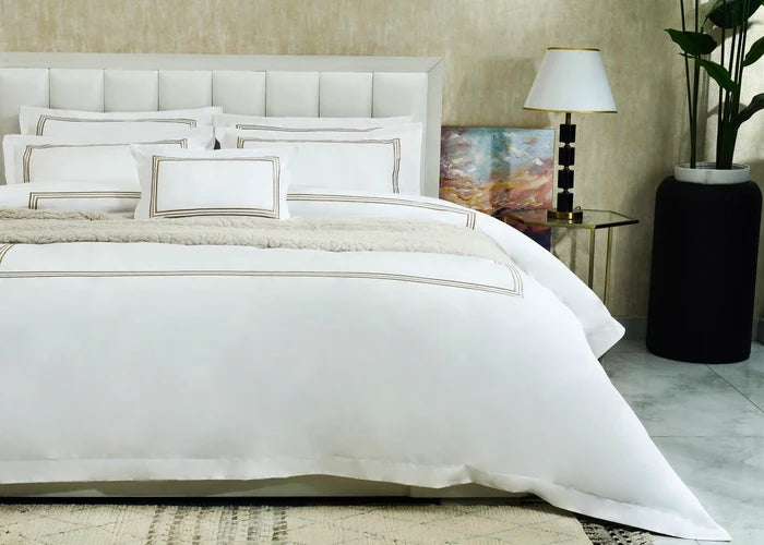 White duvet cover set with gold-striped trim and matching pillow shams