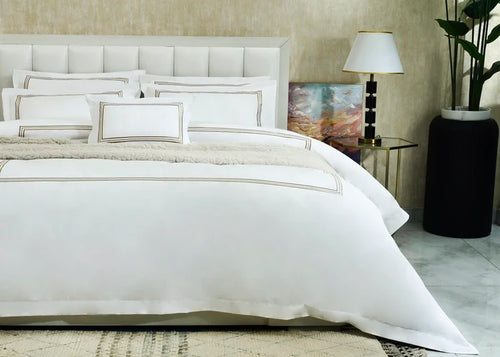 White duvet cover set with gold-striped trim and matching pillow shams