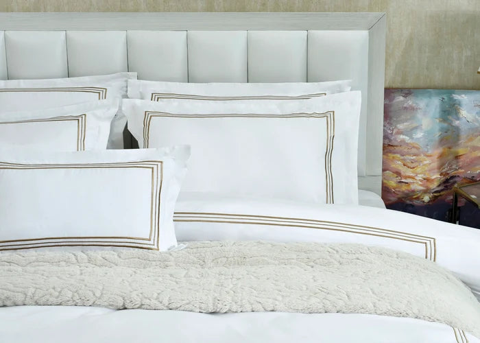 White duvet cover with gold-bordered shams and coordinating throw pillows