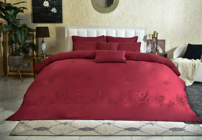 Red embroidered comforter laid on bed with coordinating pillows