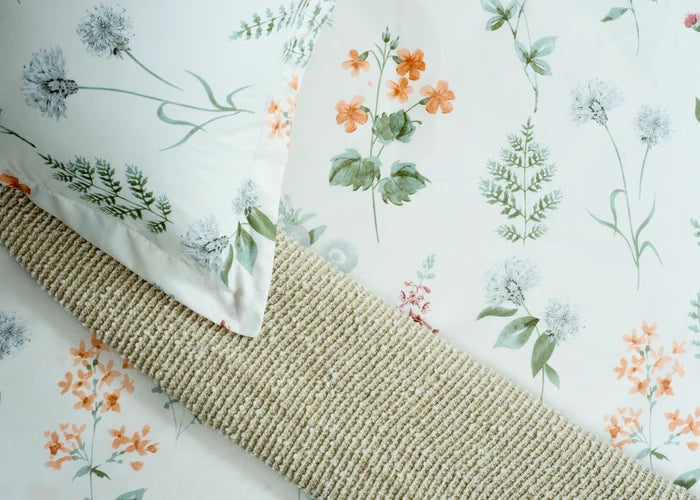 Cream floral cotton bed sheet with green and orange blooms and textured edge