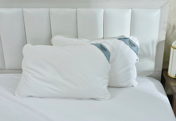 Two white duck feather pillows on bed, stitched edges and labels visible