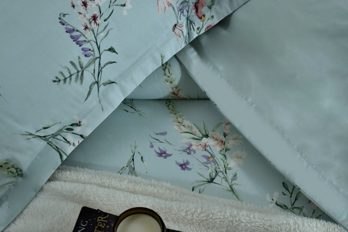 Light blue floral pillow cover detail with stitched corner and fabric fold