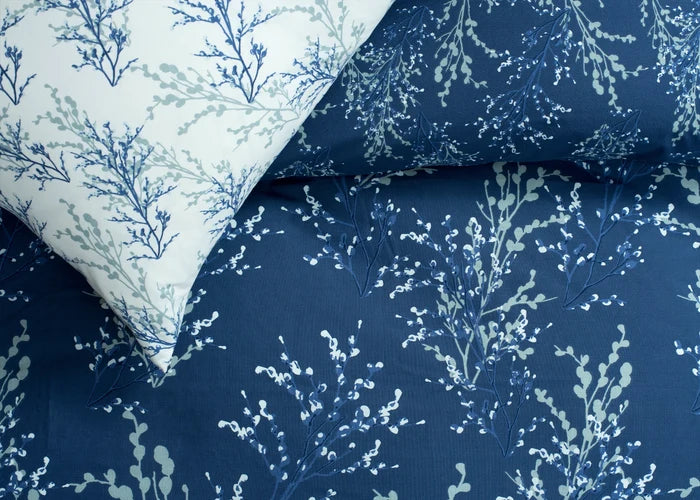 Navy cotton comforter with light botanical branch print, folded corner detail