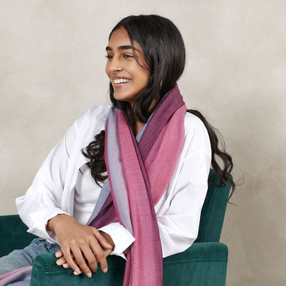 Woman wearing a pink scarf sitting on a green chair against a beige background