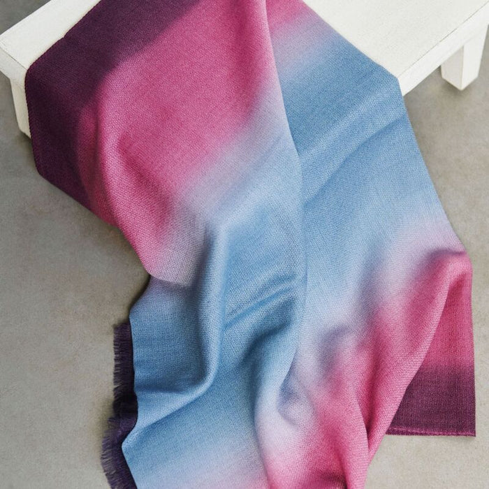 Gradient scarf transitioning from purple to pink and blue on a white surface.