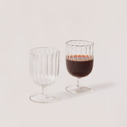 A set of two clear glass stemware items with a striped pattern on a plain background.