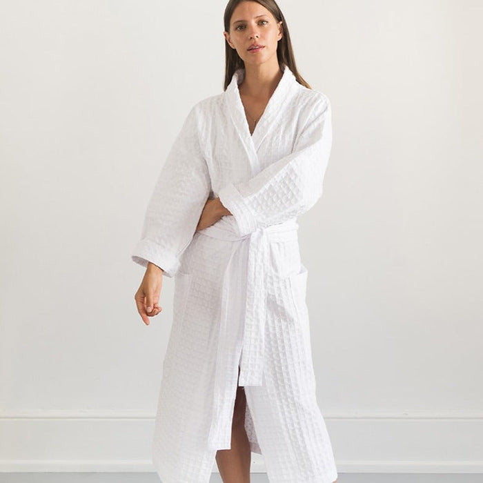 A person standing in a white room wearing a white traditional cotton dressing gown with a lattice weave pattern.