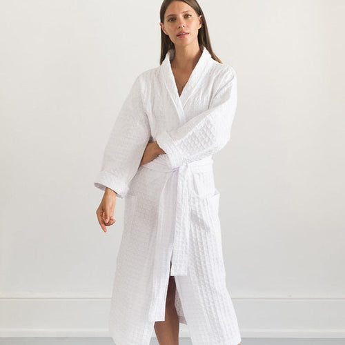 A person standing in a white room wearing a white traditional cotton dressing gown with a lattice weave pattern.