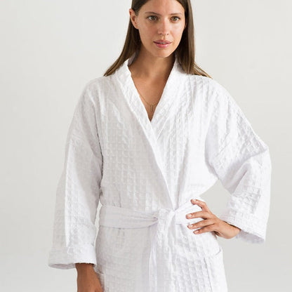 A person standing in a white room wearing a white traditional cotton dressing gown with a lattice weave pattern.