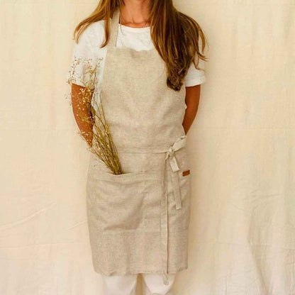 Woman wearing a linen apron in natural tan tones.