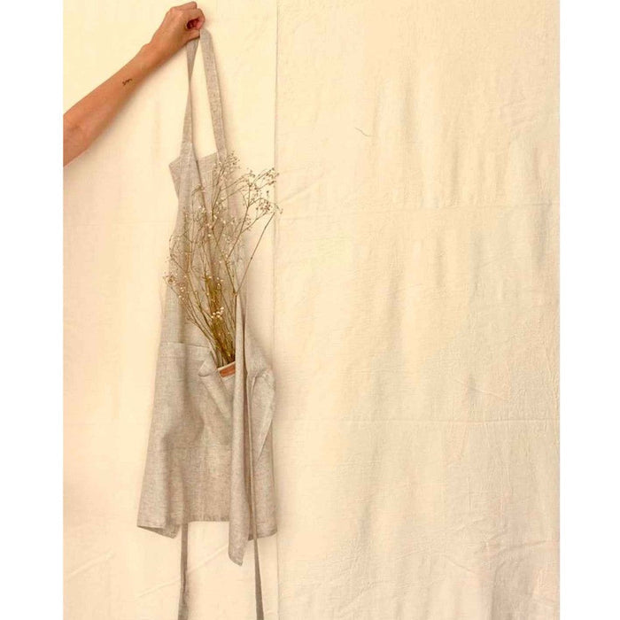 Person holding a linen apron in natural tan tones.