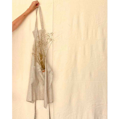 Person holding a linen apron in natural tan tones.