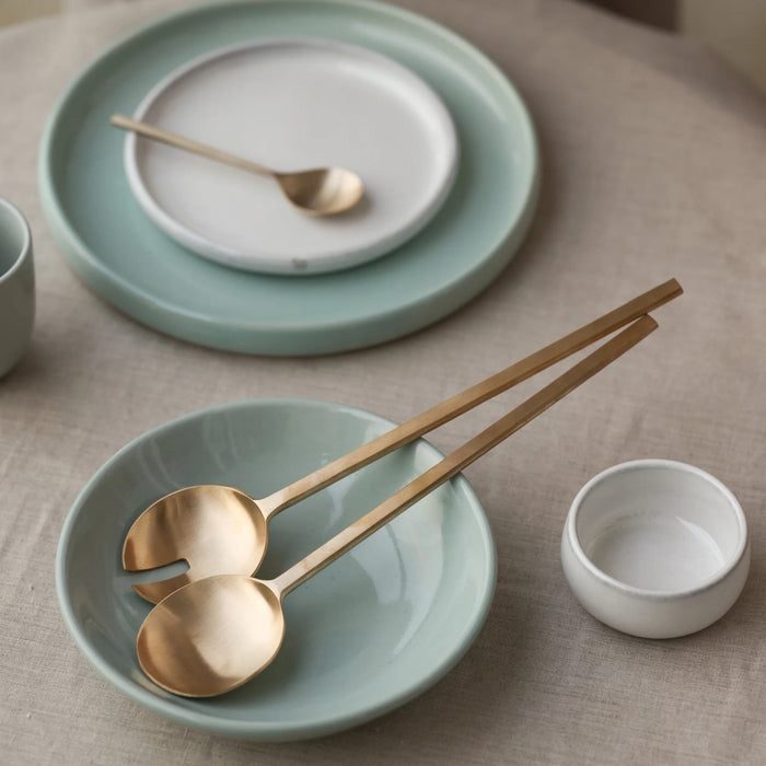 Two gold spoons in a light blue bowl.