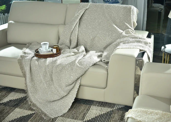Brown knitted throw blanket draped over sofa arm and seat