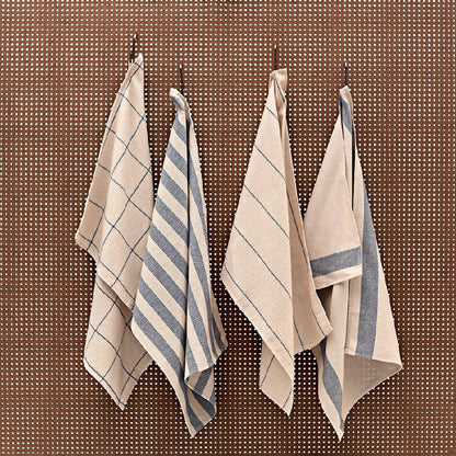 A set of four folded striped kitchen towels in natural and blue denim colors, hanging on a wall.