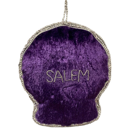 A purple velvet crystal ball ornament with silver metallic applique, featuring an eye and stars design, and the word 'Salem' on the reverse.