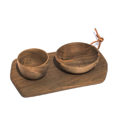 A rectangular cutting board made of walnut wood, accompanied by two wooden bowls, placed on a white background with a rope handle.