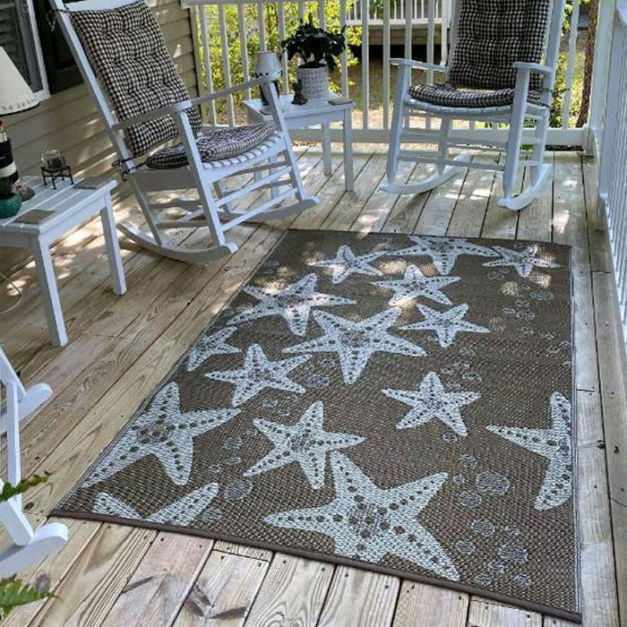 Starfish patterned rug on a wooden deck with rocking chairs and a small table.