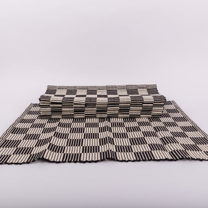A stack of checkerboard patterned placemat in black and cream on a white background.