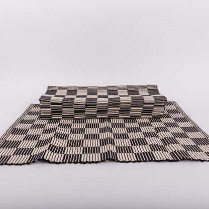 A stack of checkerboard patterned placemat in black and cream on a white background.