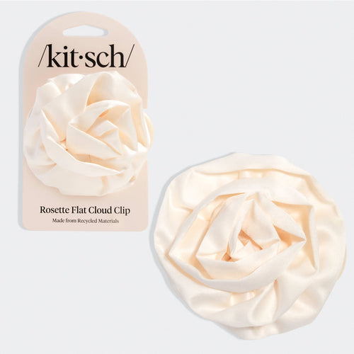 Cream-colored hair clip shaped like a soft rosette with layered, cloud-like petals. Shown next to beige packaging labeled “Kitsch” and “Rosette Flat Cloud Clip – Made from Recycled Materials.”
