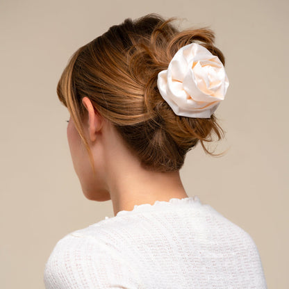 Woman with a white rose in her hair against a beige background