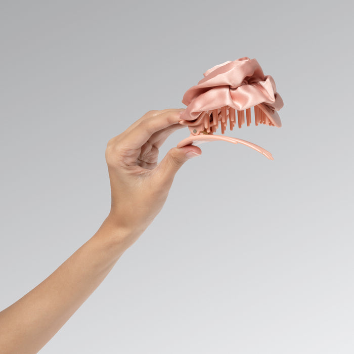 Hand holding a decorative hair accessory with a gray background